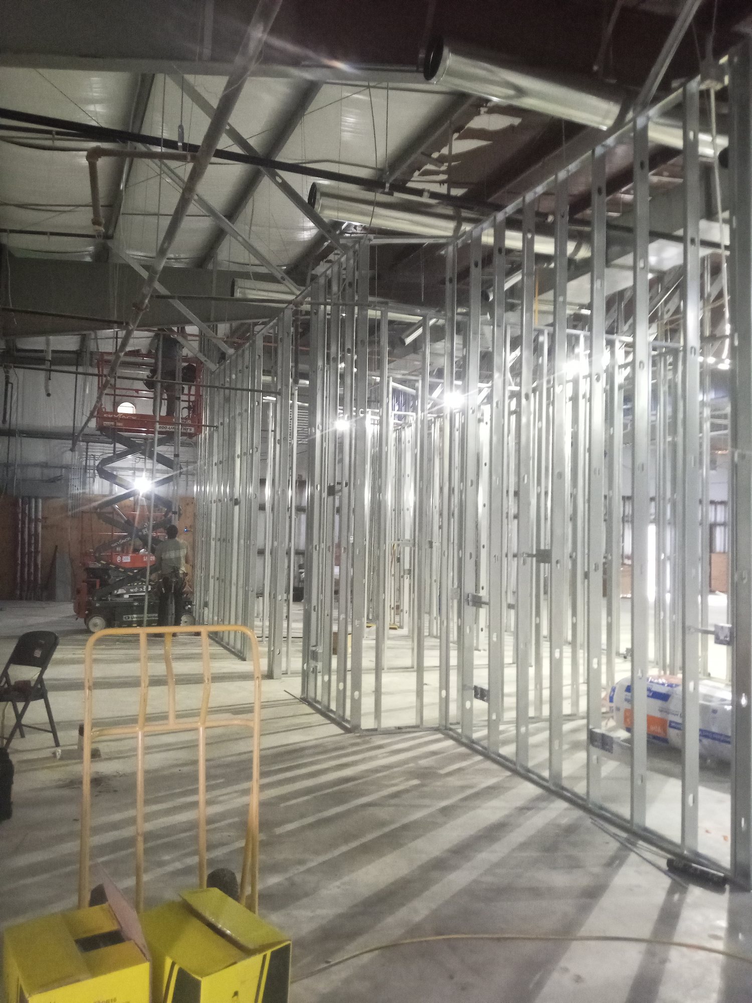 Metal-stud framing dividing the open hall into rooms